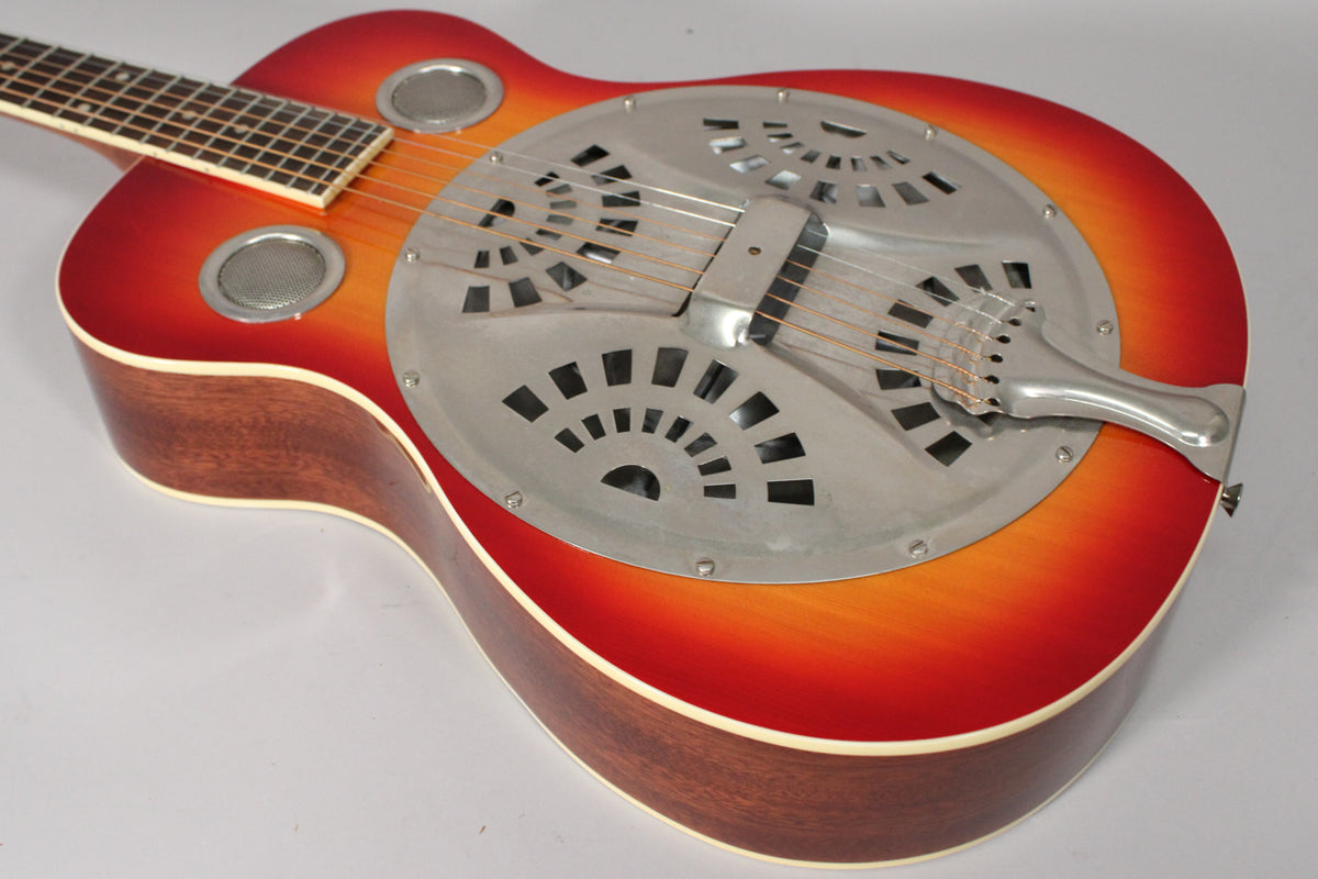 The resonator guitar's cherry sunburst body and mahogany sides are visible, with a metal cover plate and two sound screens.