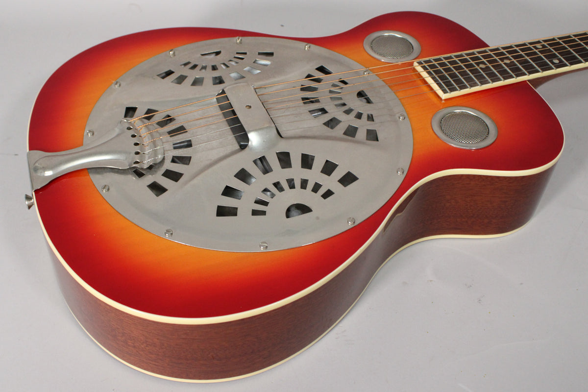 The cherry sunburst resonator guitar's body is angled, showing the metal coverplate with fanned cutouts and two round soundholes.