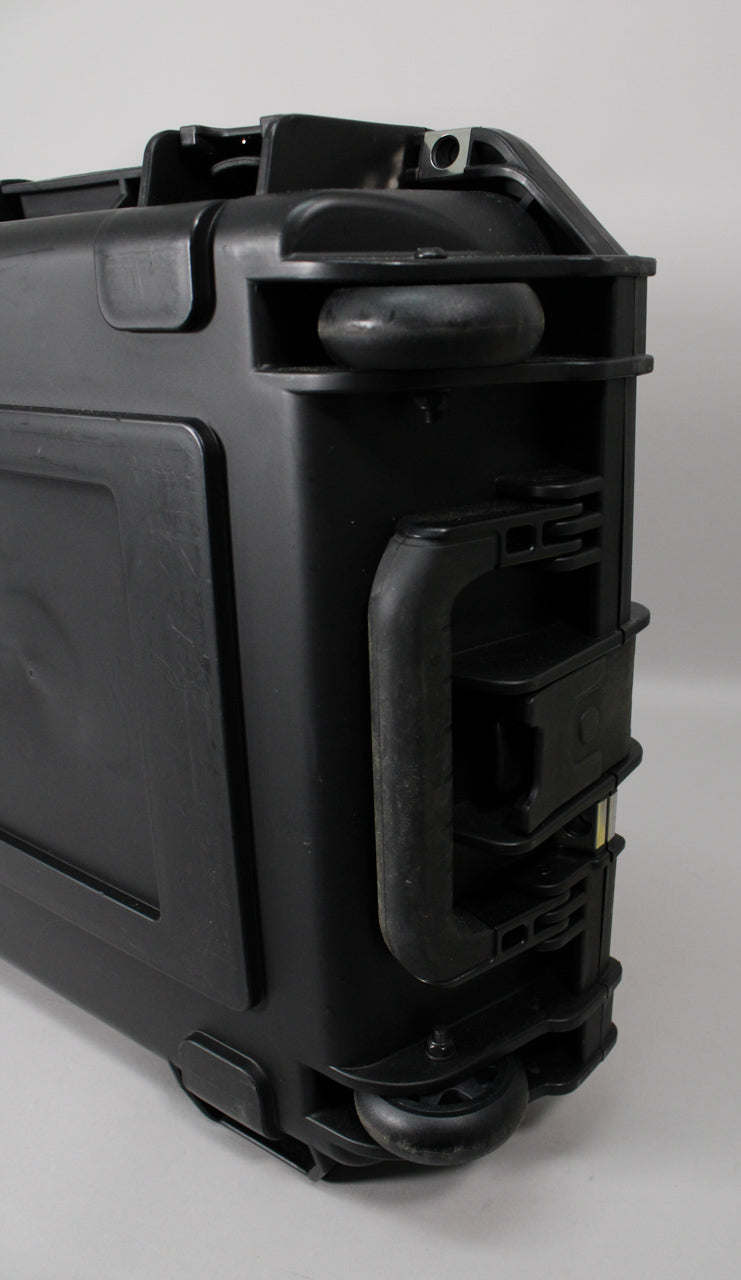 Close-up of the black hard case's end, showing two wheels, a retractable handle, and a metal-ringed padlock hole.