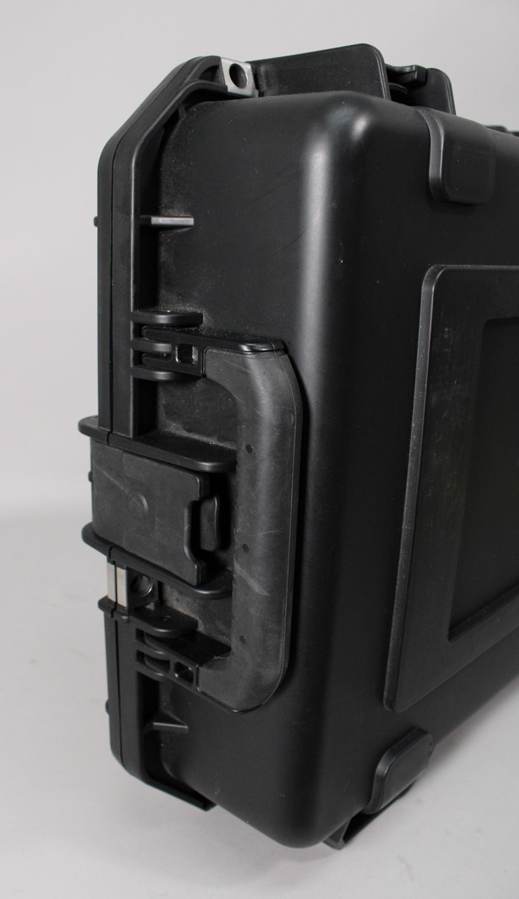 Close-up of the black hard case's side, showing a rubberized handle, two latches, and a metal padlock eyelet.