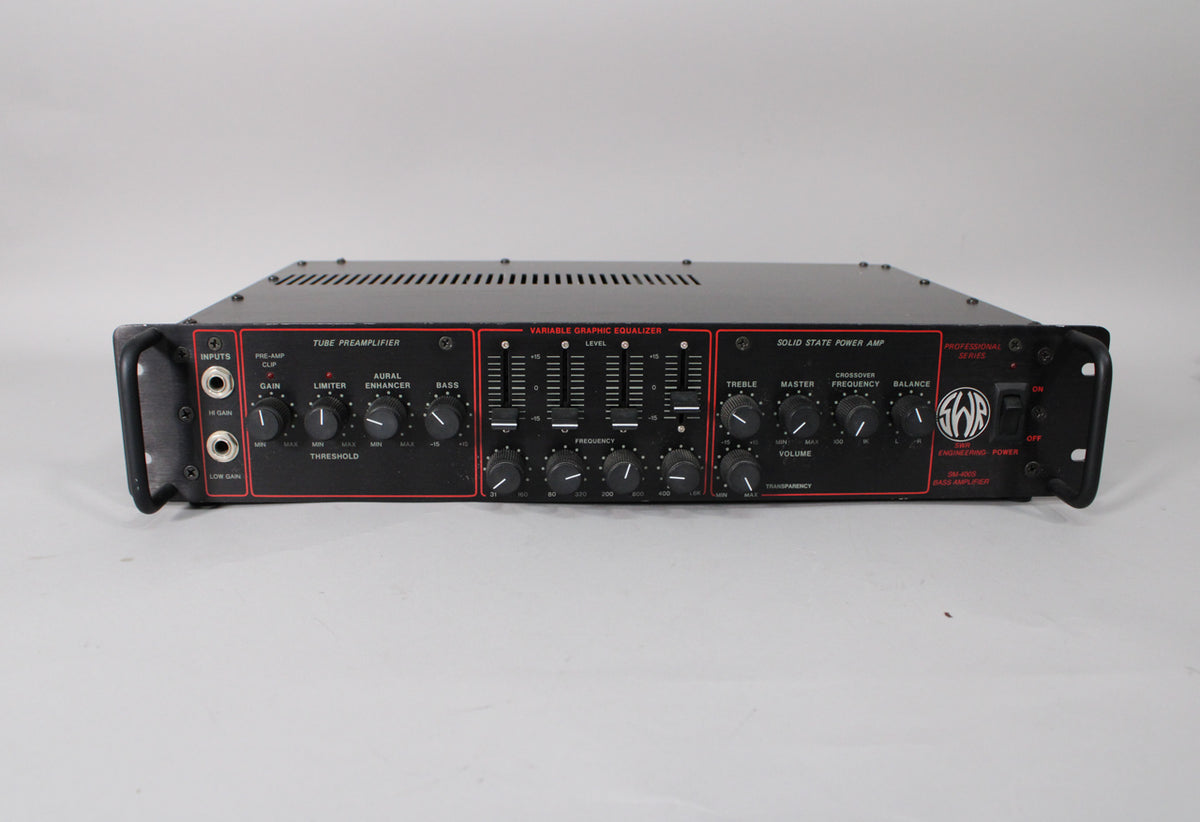 A black rackmount bass amplifier, shown front-on, with a red-bordered control panel featuring many knobs, sliders, and two input jacks.