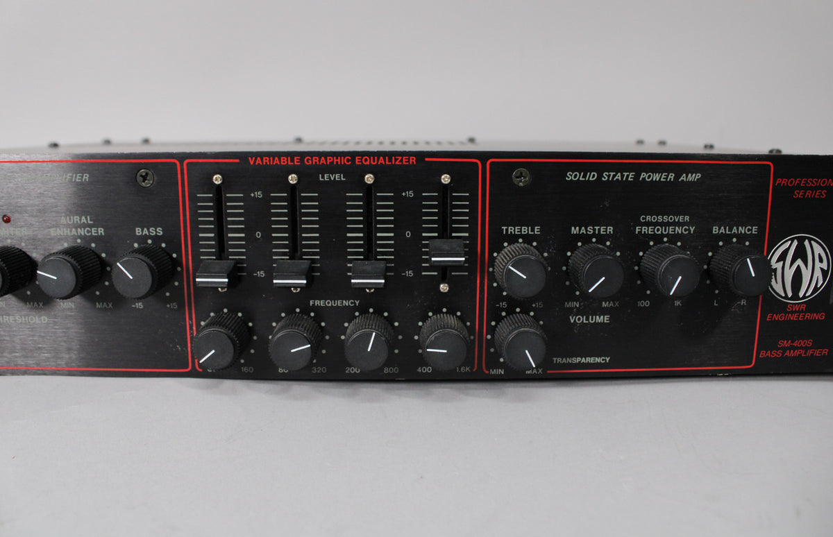 The black rackmount amplifier's front panel is visible, featuring numerous black knobs and five vertical faders with red accents.