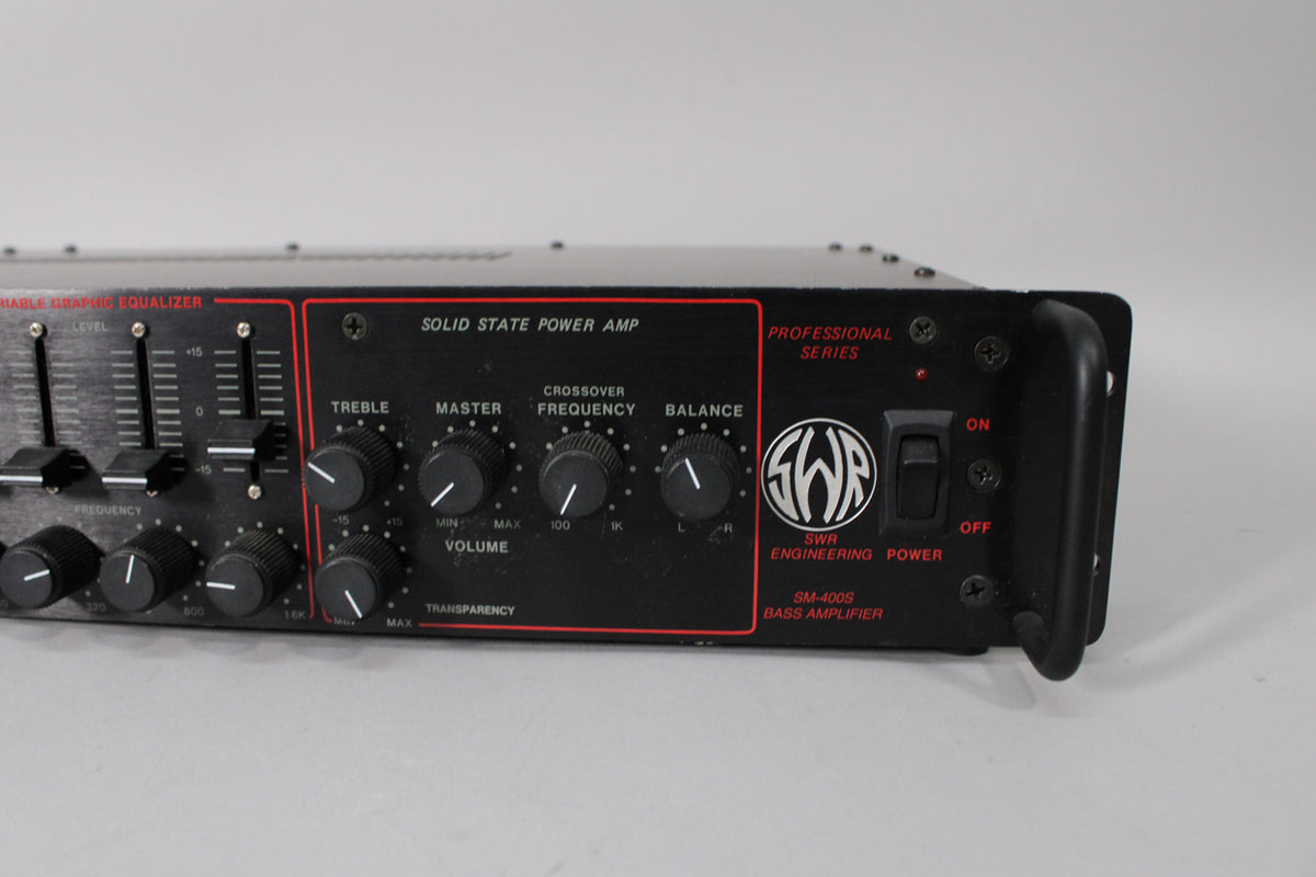 Close-up of the black rackmount amp's front panel, showing a graphic equalizer, various knobs, and a power switch.
