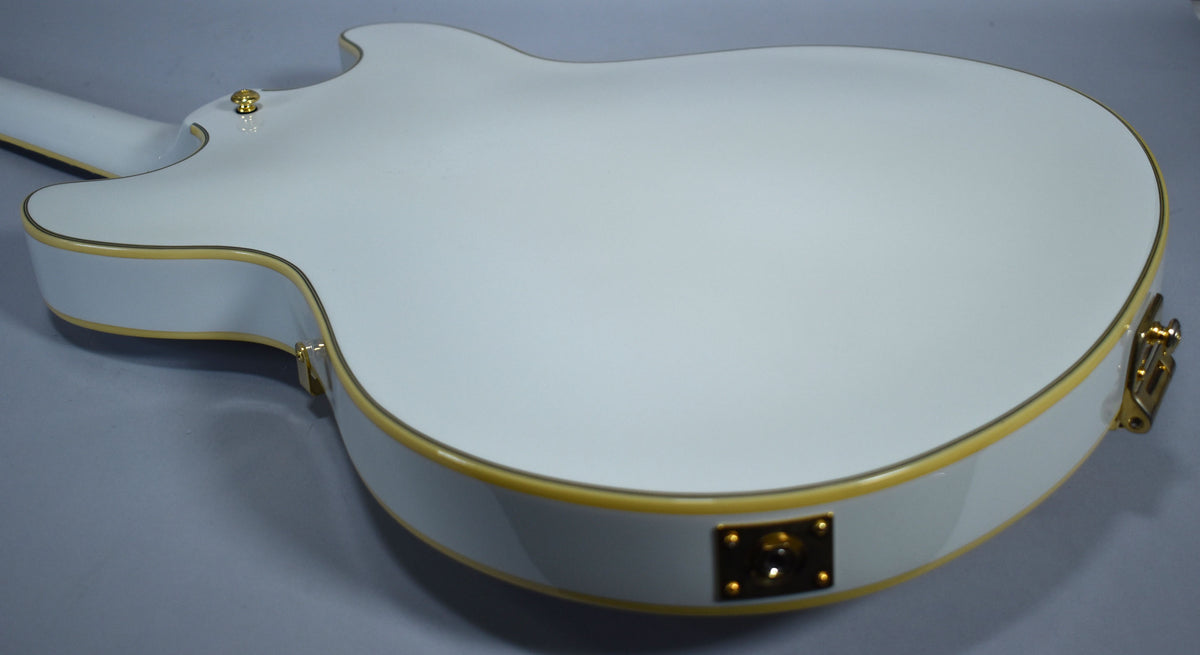 The back of a glossy white guitar with gold binding, showing the neck joint and a gold output jack plate.