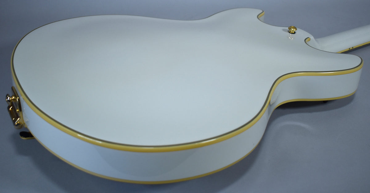 Upper body of a glossy white hollow-body electric guitar, showing gold binding and a gold strap button.