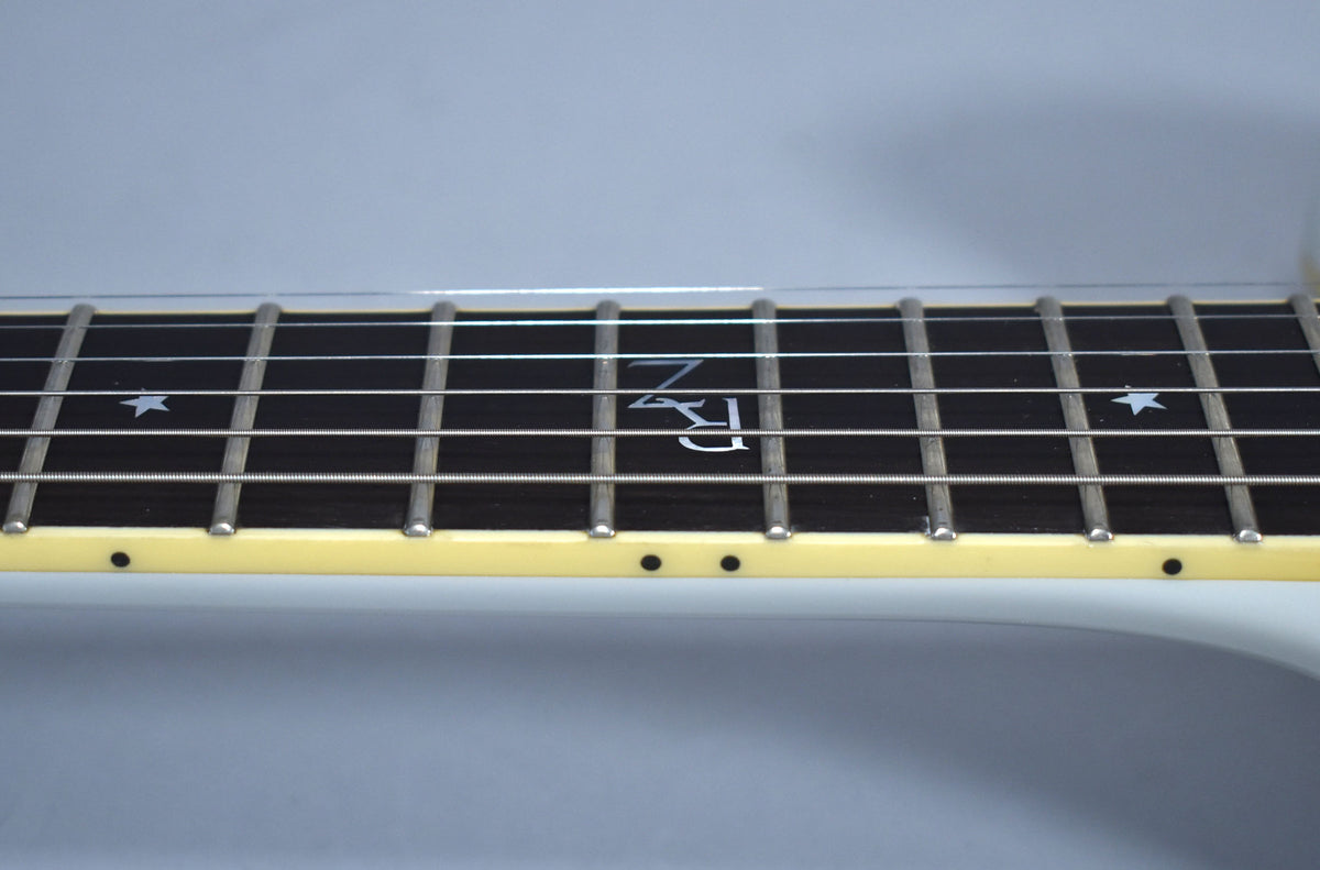 Close-up of the guitar's dark fretboard, showing white star inlays and a stylized "RZ" inlay, with light cream binding and side dots.