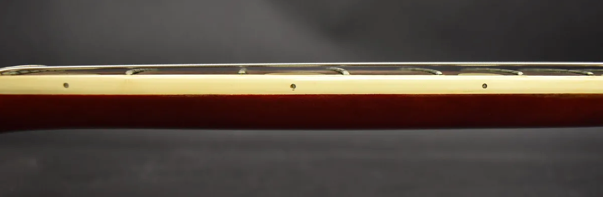 Close-up of the guitar's cherry red neck and cream binding, showing the side dot markers and frets with strings.