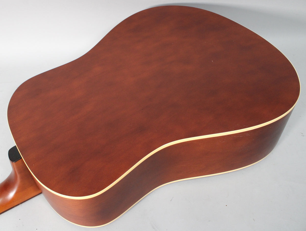 The acoustic guitar's dark reddish-brown back and side are visible, with light binding and a few minor scuffs.
