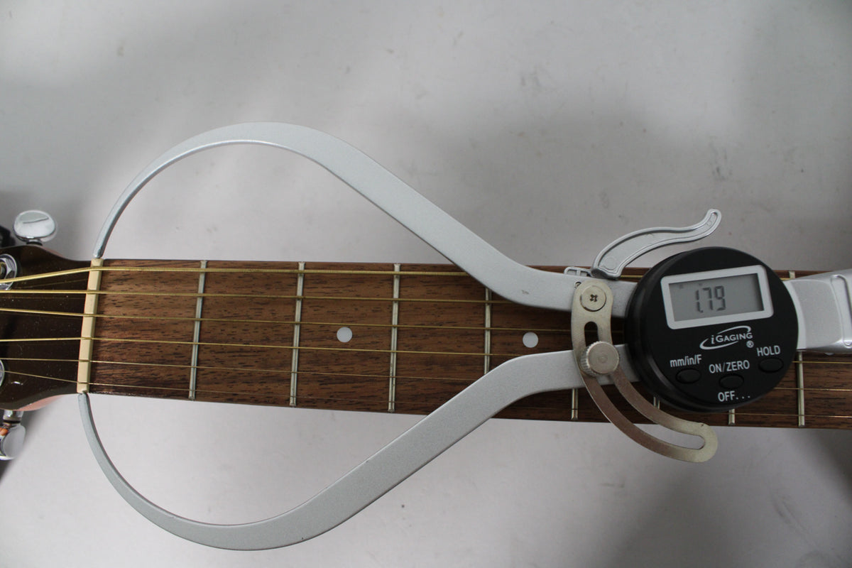 A digital caliper measures the dark brown fretboard, showing a reading of 1.79, with light wear visible on the frets.