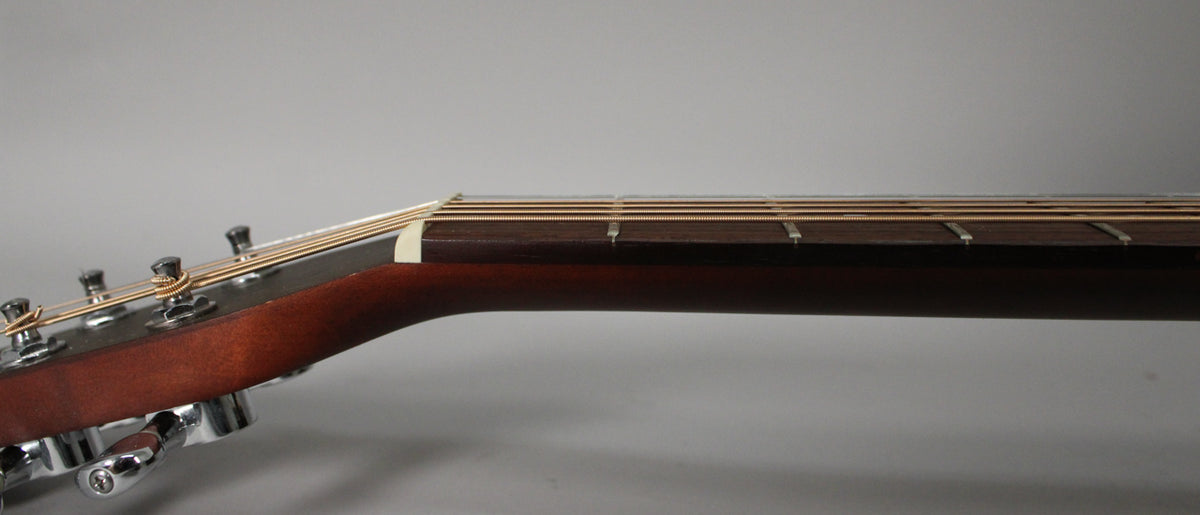 The guitar's headstock and neck are viewed from the side, showing the dark fretboard, light nut, and chrome tuners.