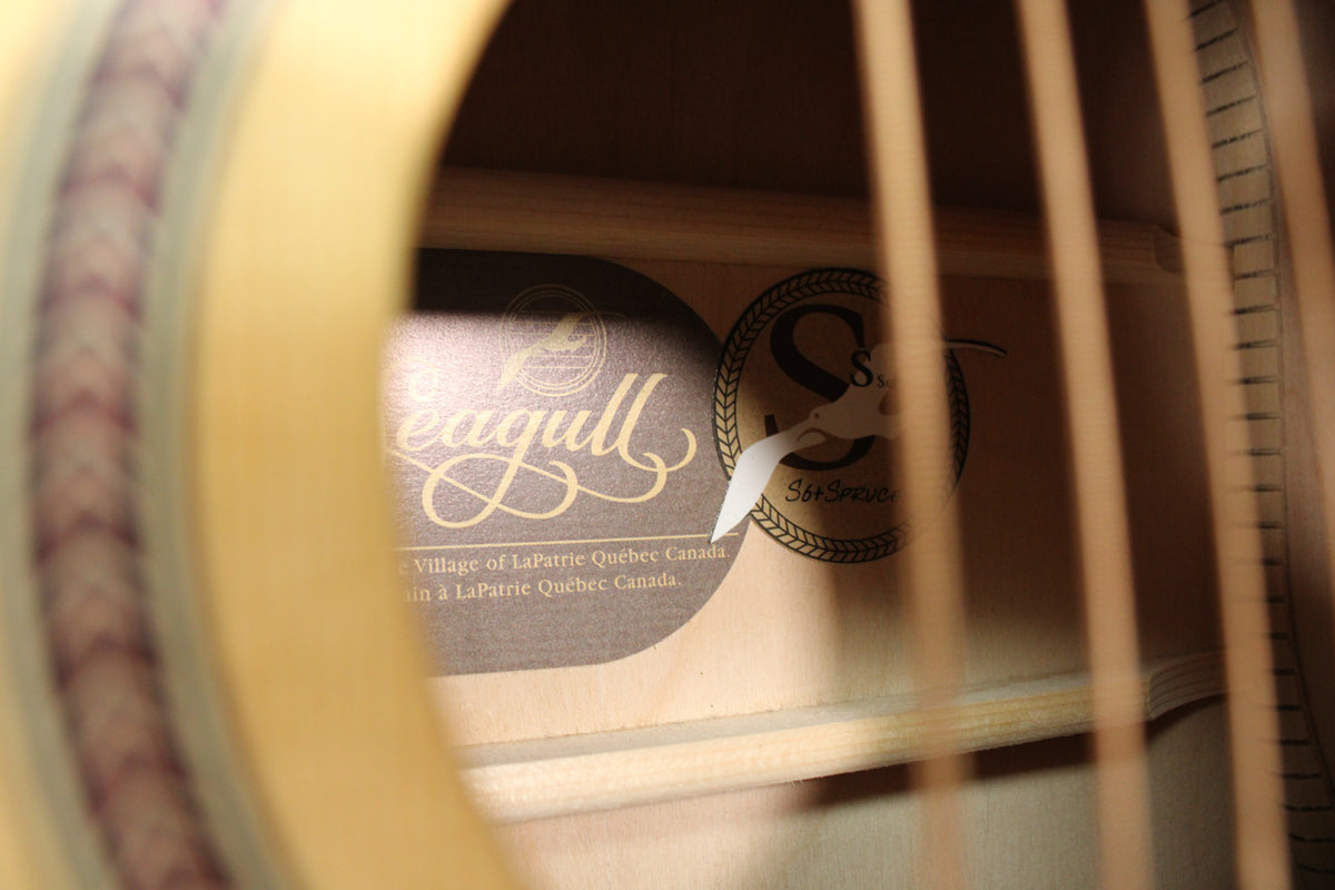 Looking into the soundhole, the light wood interior shows two labels and a white sticker partially covering one.