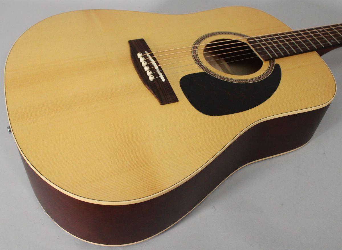The acoustic guitar's light-colored spruce top and dark sides are visible from the upper bout, with a black pickguard and bridge.