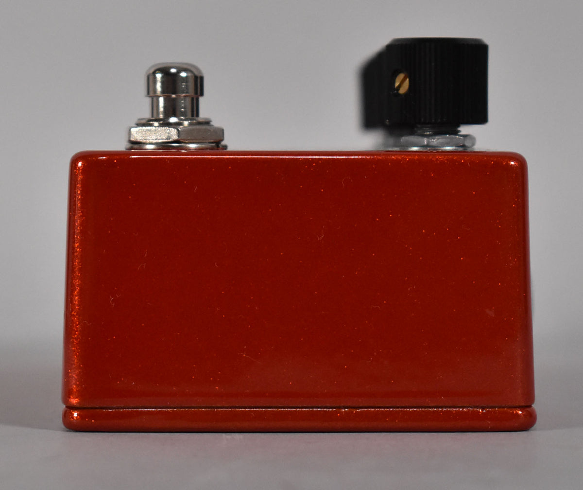 The Selah Scarlett Love V3 Overdrive Pedal, a metallic orange rectangular box, is shown from the back with a chrome footswitch and black knob.