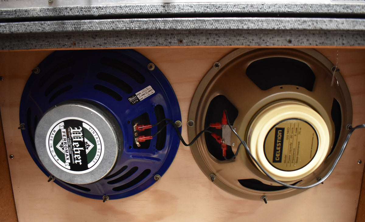 Close-up of the cabinet's interior, showing one blue and one gold speaker, both wired with red and black connectors.