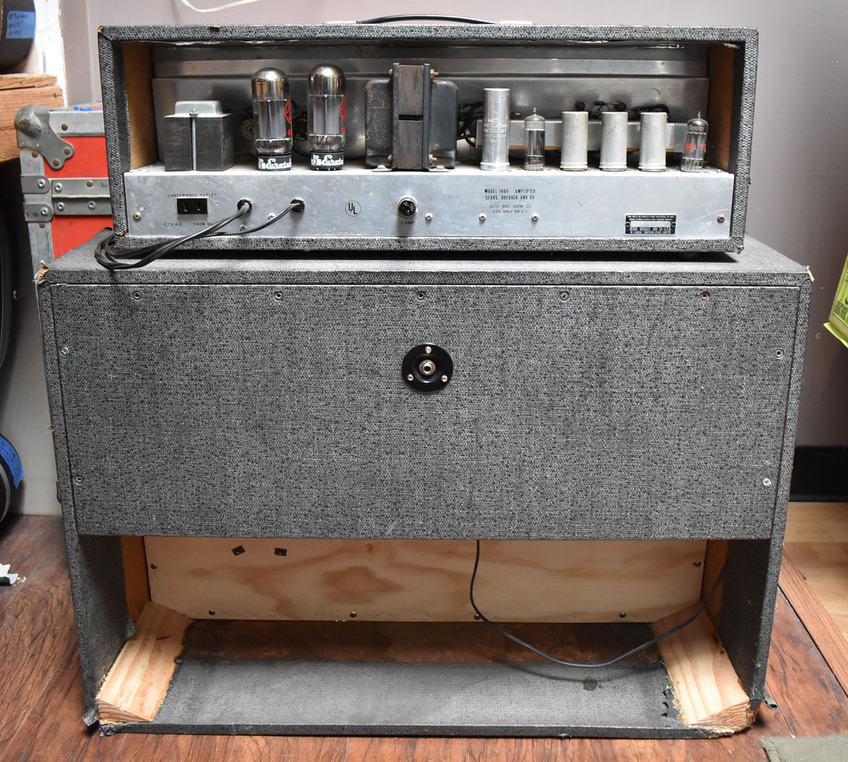 Rear view of the gray tweed amplifier head, revealing its vacuum tubes, and the matching 2x12 cabinet with an open back.