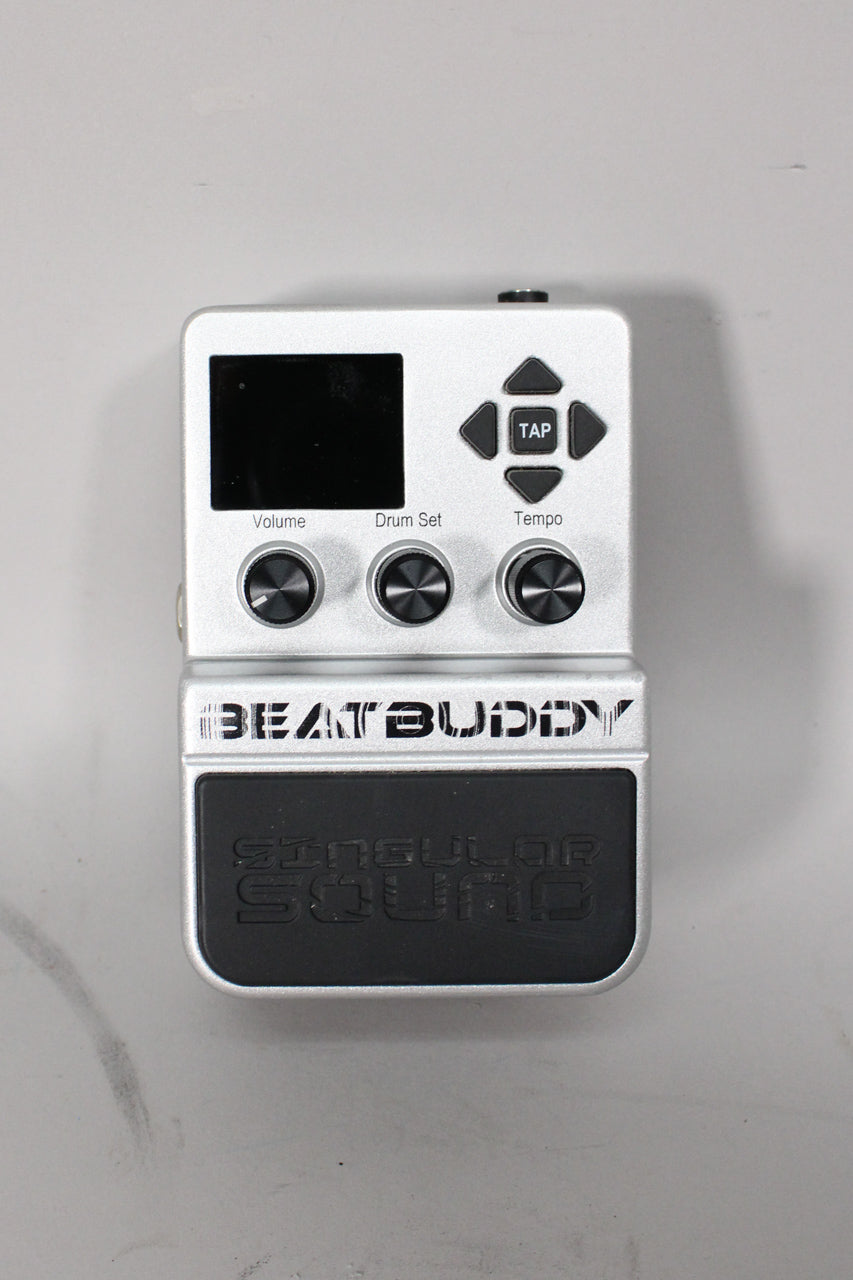 Top-down view of a silver pedal with a black screen, three black knobs, a directional pad, and a large black foot switch.