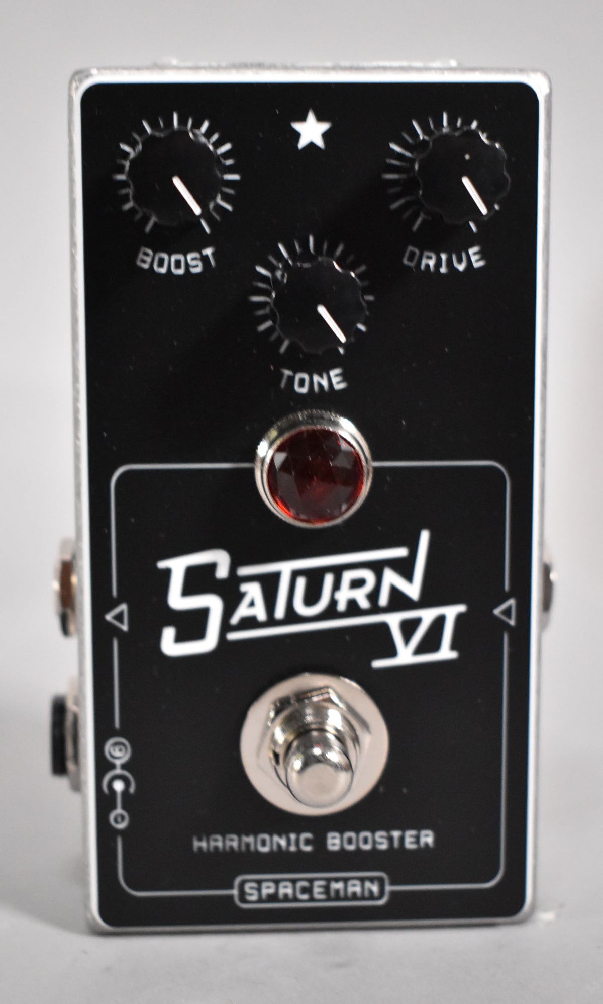 A black guitar pedal with a silver casing, featuring three black control knobs, a red jewel LED, and a footswitch.