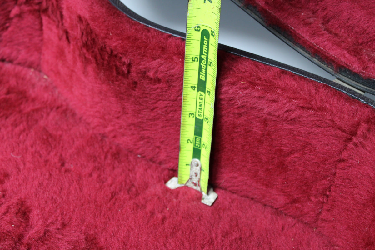A tape measure shows the case's red plush lining is 6 inches deep, with some wear and light debris visible.