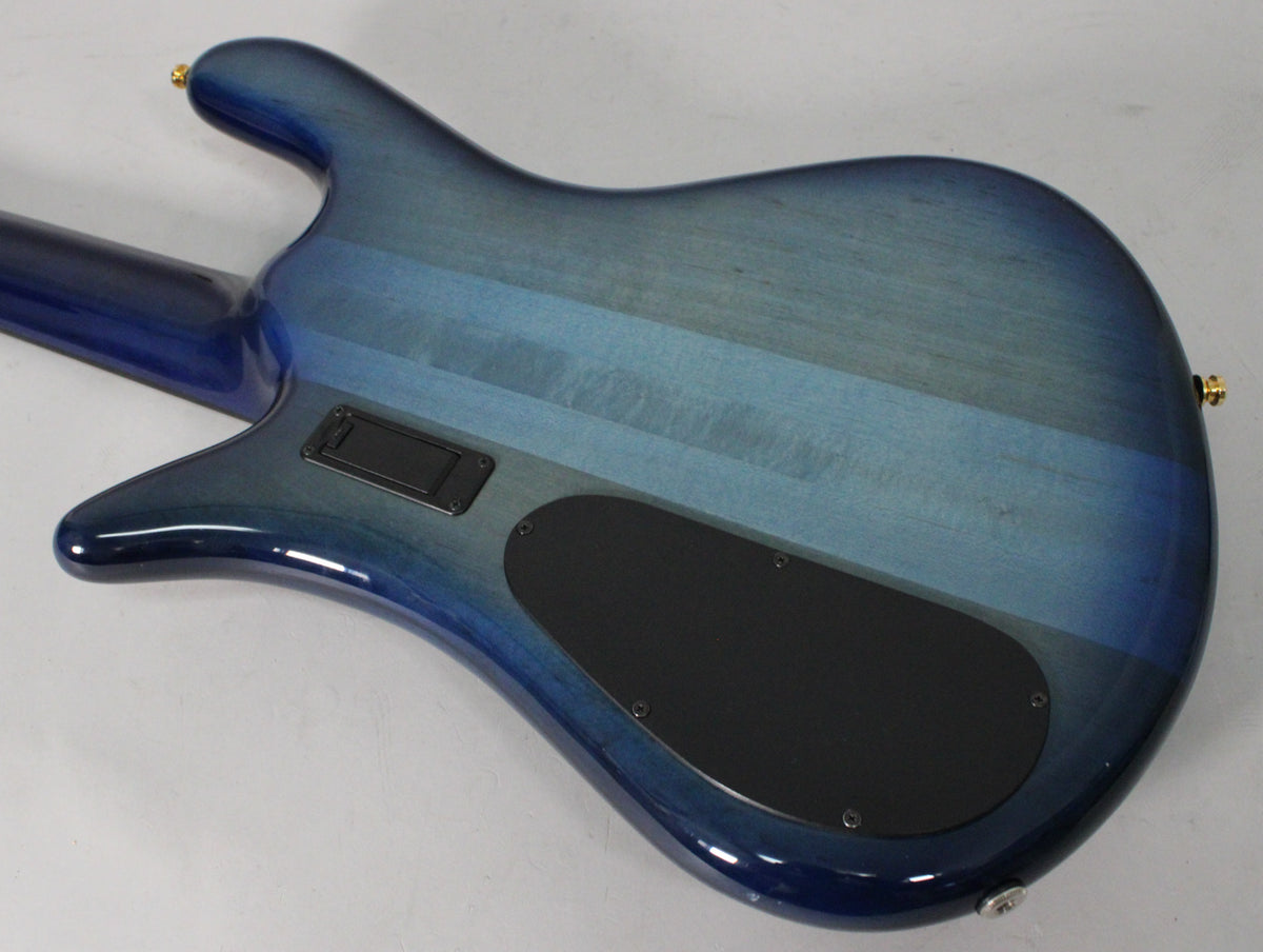 The bass guitar's back, showing a blue fade gloss finish with horizontal wood grain, two black control plates, and gold hardware.