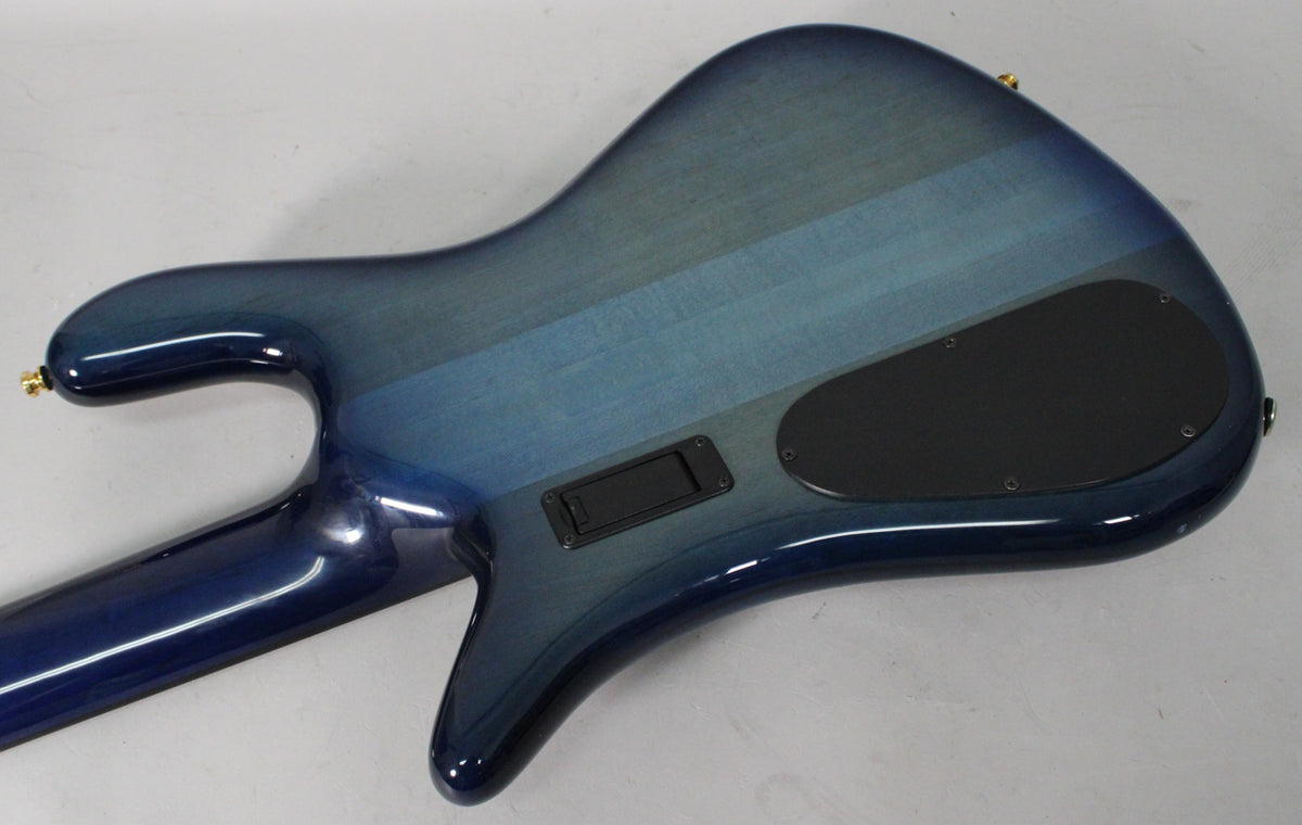 The bass guitar's back shows a blue fade gloss finish with lighter blue wood grain stripes, a black control plate, and a battery compartment.