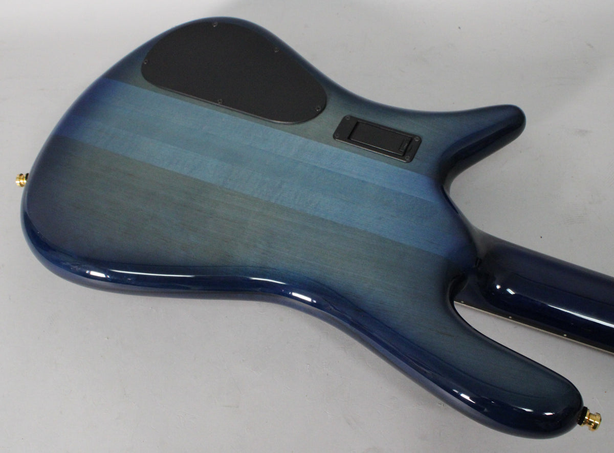 The bass guitar's back shows a blue fade gloss finish with horizontal wood grain, black control covers, and a gold strap button.