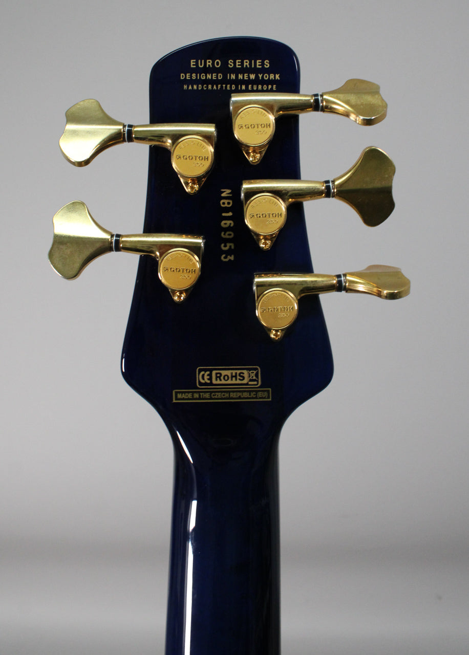 Rear view of the bass headstock and upper neck, showing a dark blue gloss finish and five gold-colored tuning machines.
