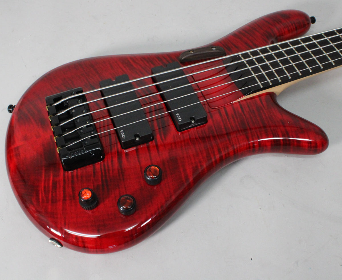 The upper body of a glossy red flame maple bass, with two black EMG pickups and three black control knobs.