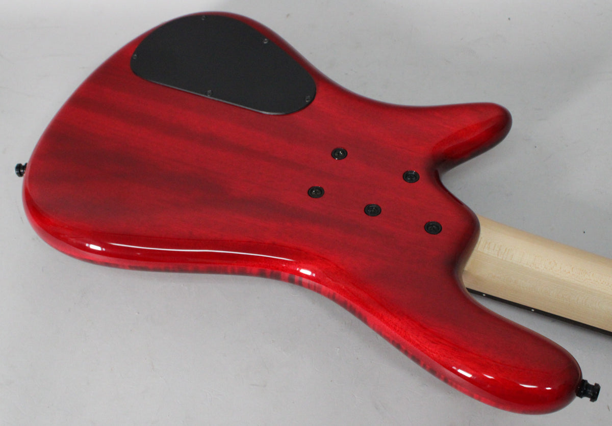 The bass guitar's glossy cherry flame back is angled, showing the black control plate, five neck bolts, and a light wood neck.