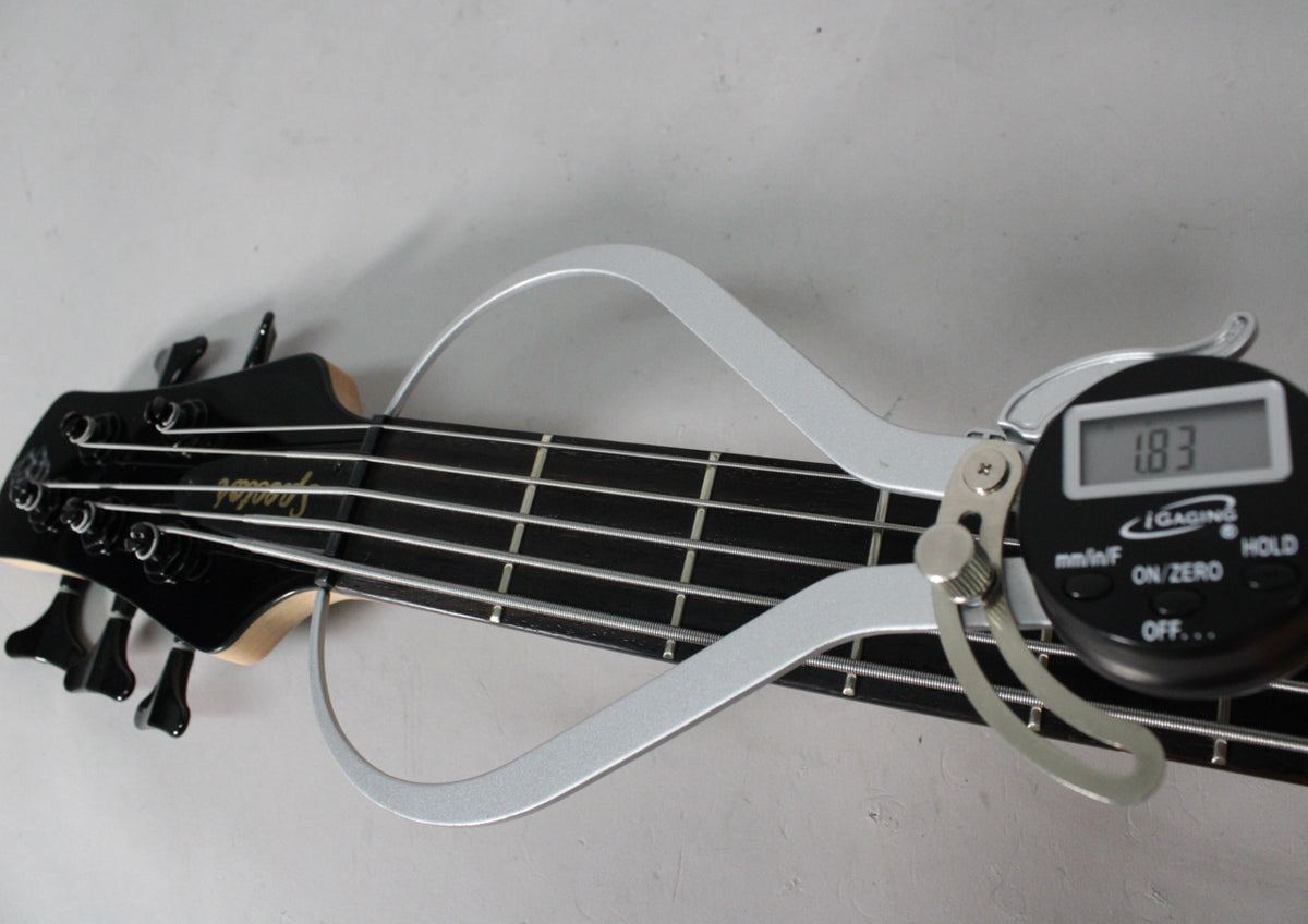 Close-up of the bass headstock and fretboard with a digital caliper measuring fret height at 1.83mm.