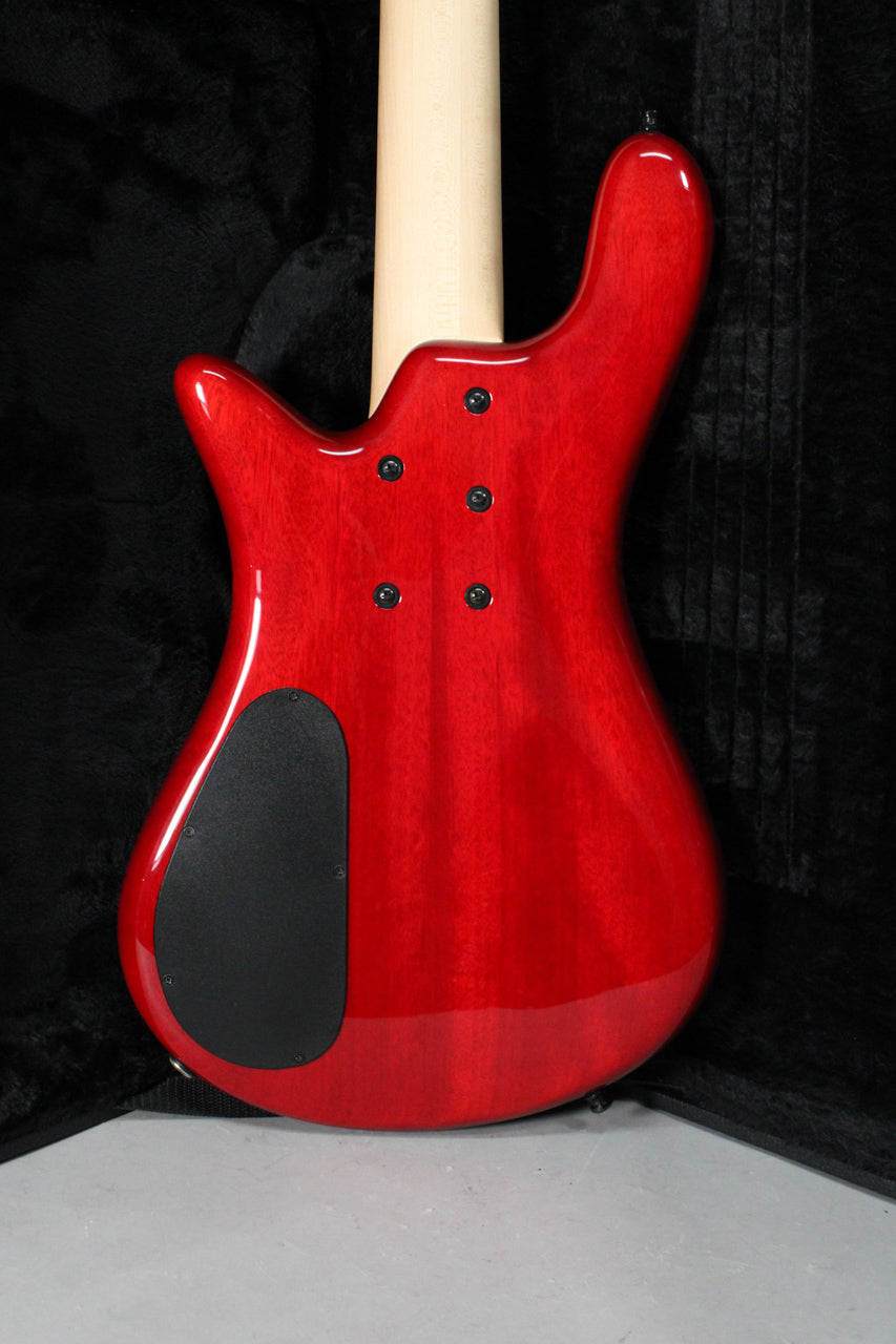 The bass guitar's back is shown, revealing a glossy black cherry flame finish, a natural wood neck, and a black control cavity cover.