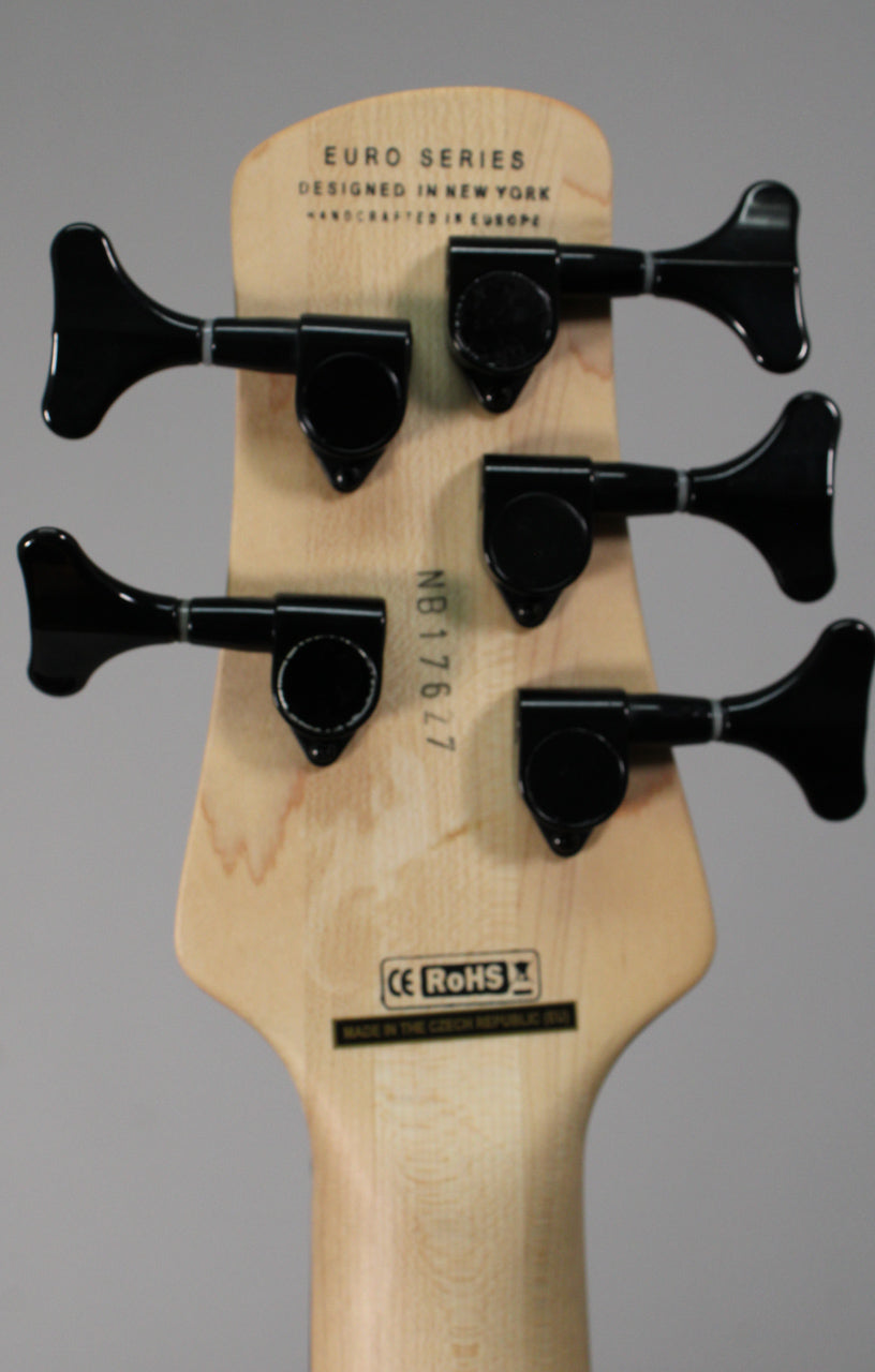 The back of a light wood headstock with five black tuning machines, showing a serial number and "CE RoHS" sticker.
