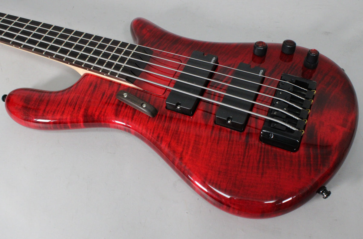 The bass's cherry flame finish is visible from the neck joint to the bottom strap button, with two black pickups and four black control knobs.
