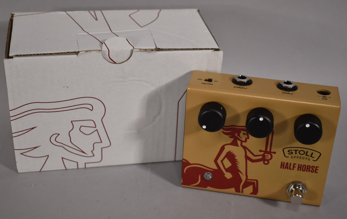 A gold guitar pedal with three black knobs and a red centaur graphic, next to its white cardboard box.