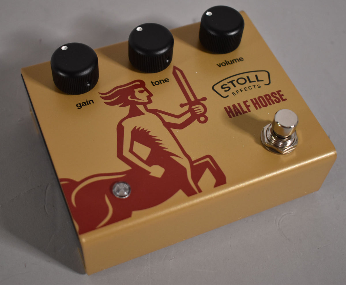 A gold-colored pedal with a red centaur graphic, three black control knobs, and a chrome footswitch, viewed from above.