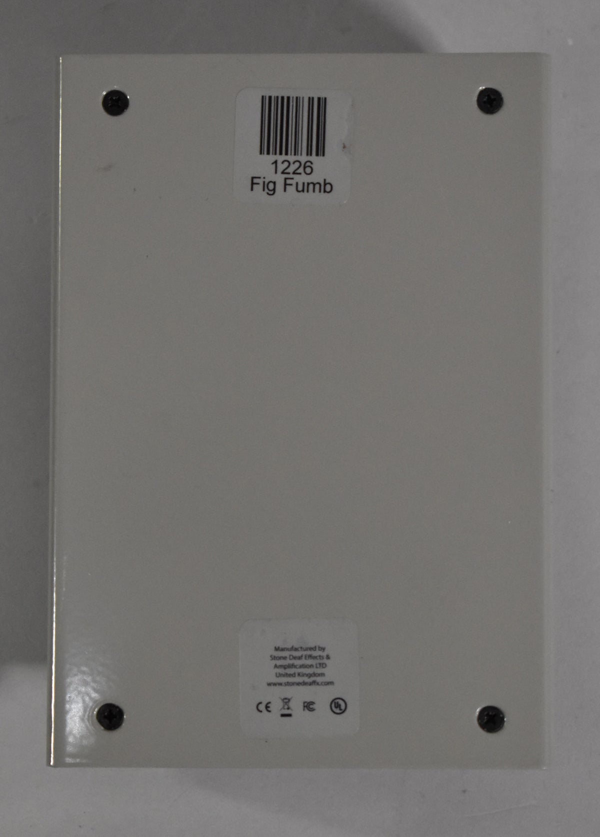 The pedal's light grey underside is visible, secured by four black Phillips head screws at each corner.