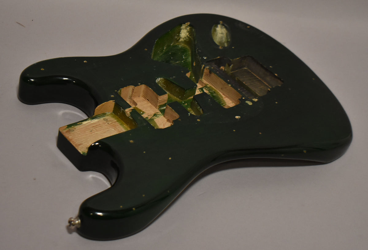 The translucent green S-style body is angled, revealing the HSH routing and Floyd Rose tremolo cavity, with some paint wear.