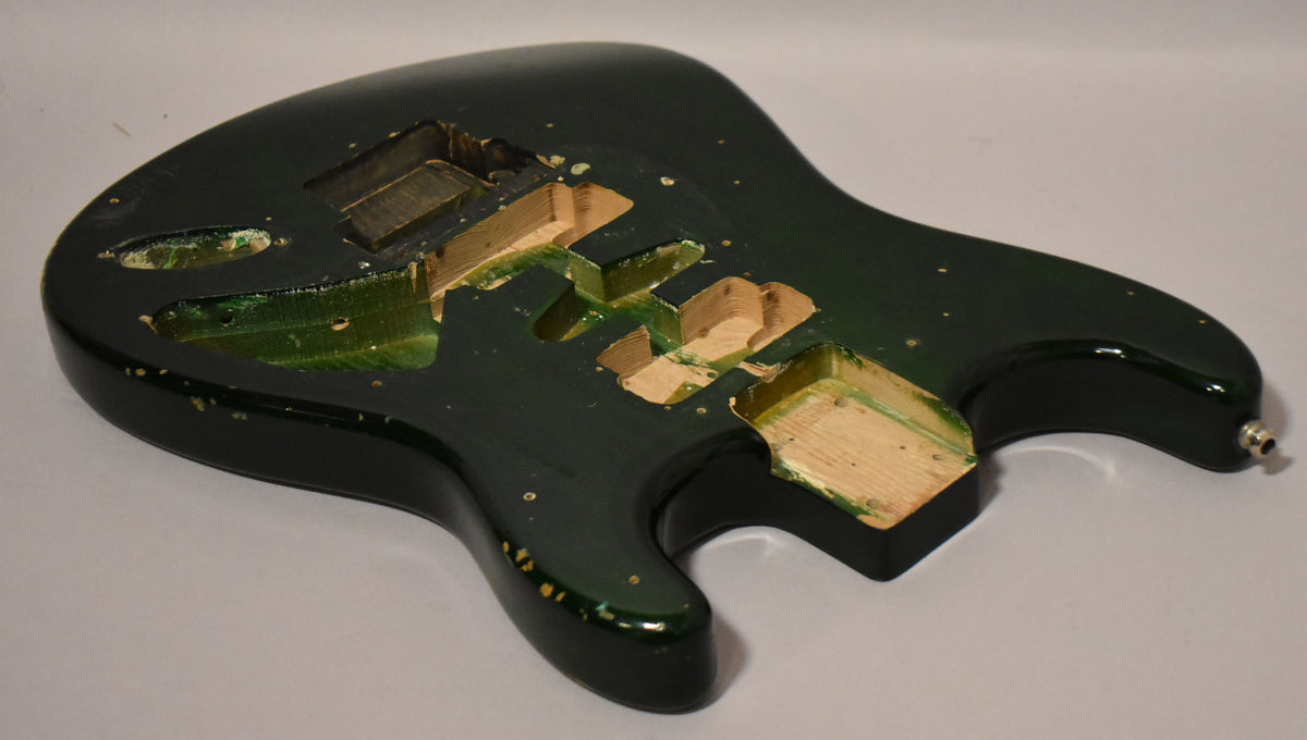 The translucent green S-style guitar body is shown from above, revealing HSH routing and a visible output jack.