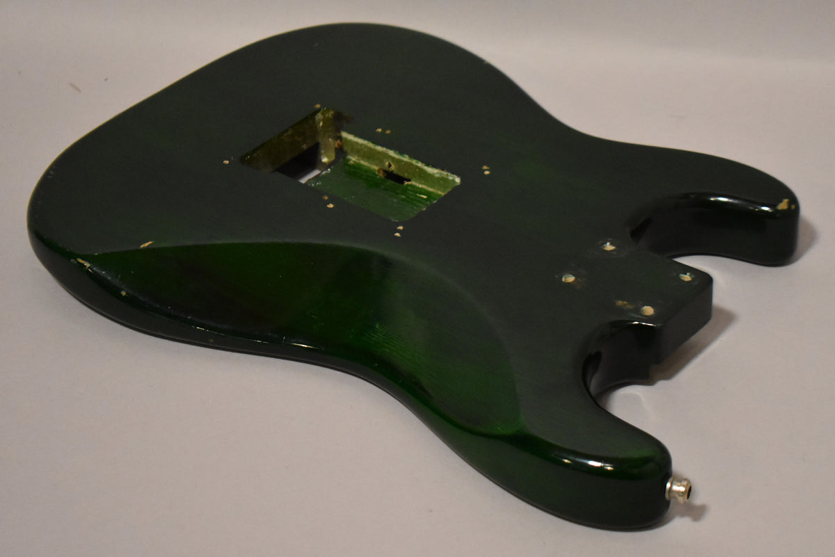 The translucent green S-style guitar body, viewed from the upper bout, shows a Floyd Rose route and HSH pickup cavities.