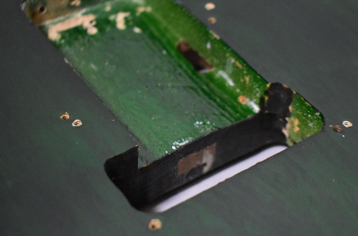 Close-up of the translucent green S-style body's bridge pickup cavity, showing exposed wood and wear around the edges.