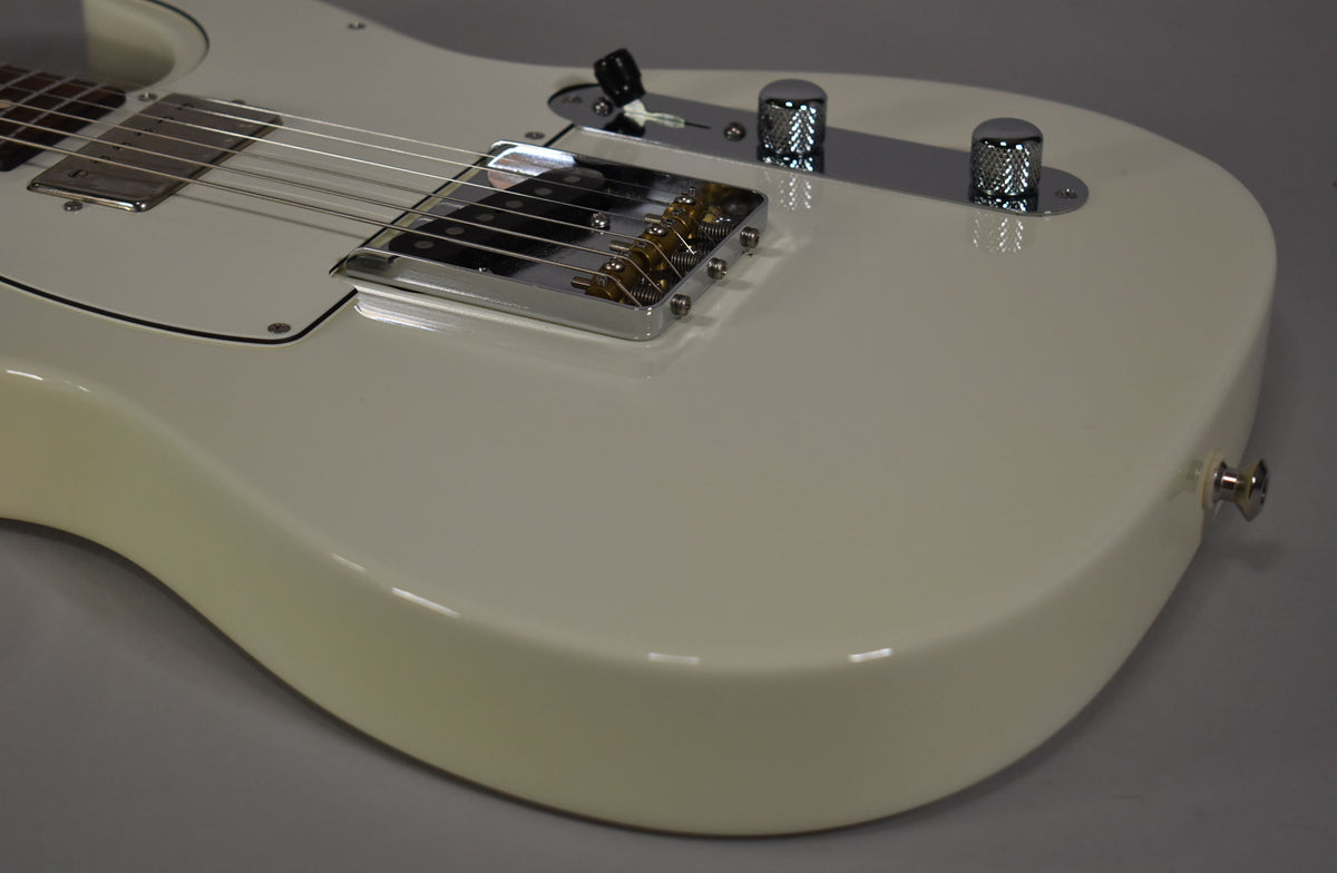 Close-up of the guitar's lower body, showing the Olympic White finish, chrome bridge, knurled control knobs, and output jack.