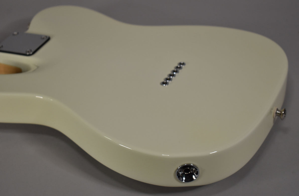 The back of the Olympic White guitar body, showing the chrome neck plate, six string-through-body ferrules, and output jack.