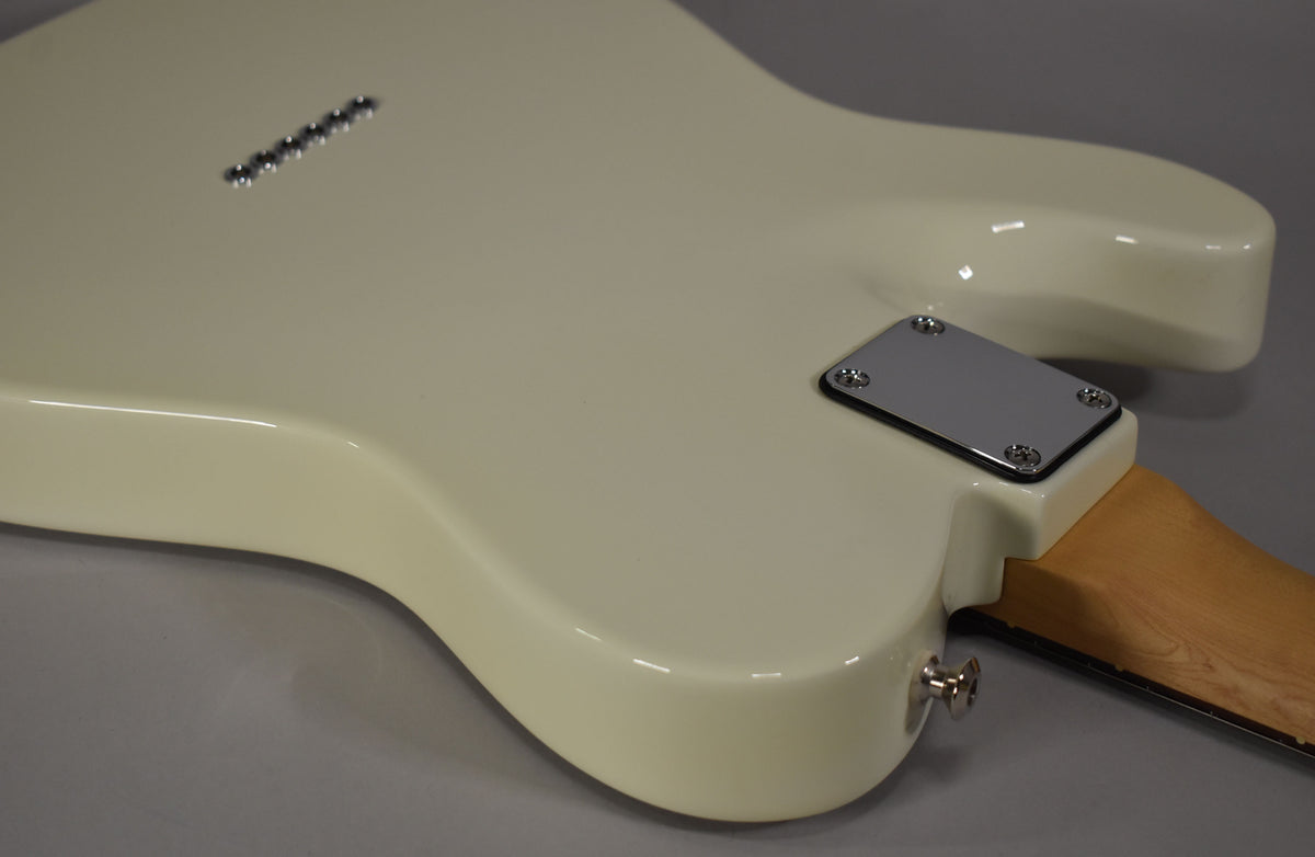 The back of the Olympic White guitar body, showing the chrome neck plate, string-through-body ferrules, and strap button.