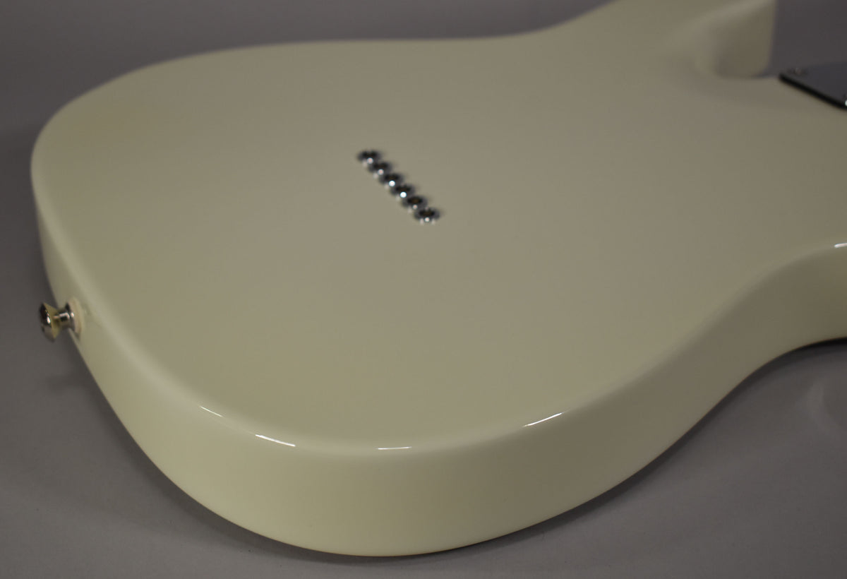 The Olympic White guitar body's lower bout and side are shown from above, with six chrome string ferrules visible on the back.