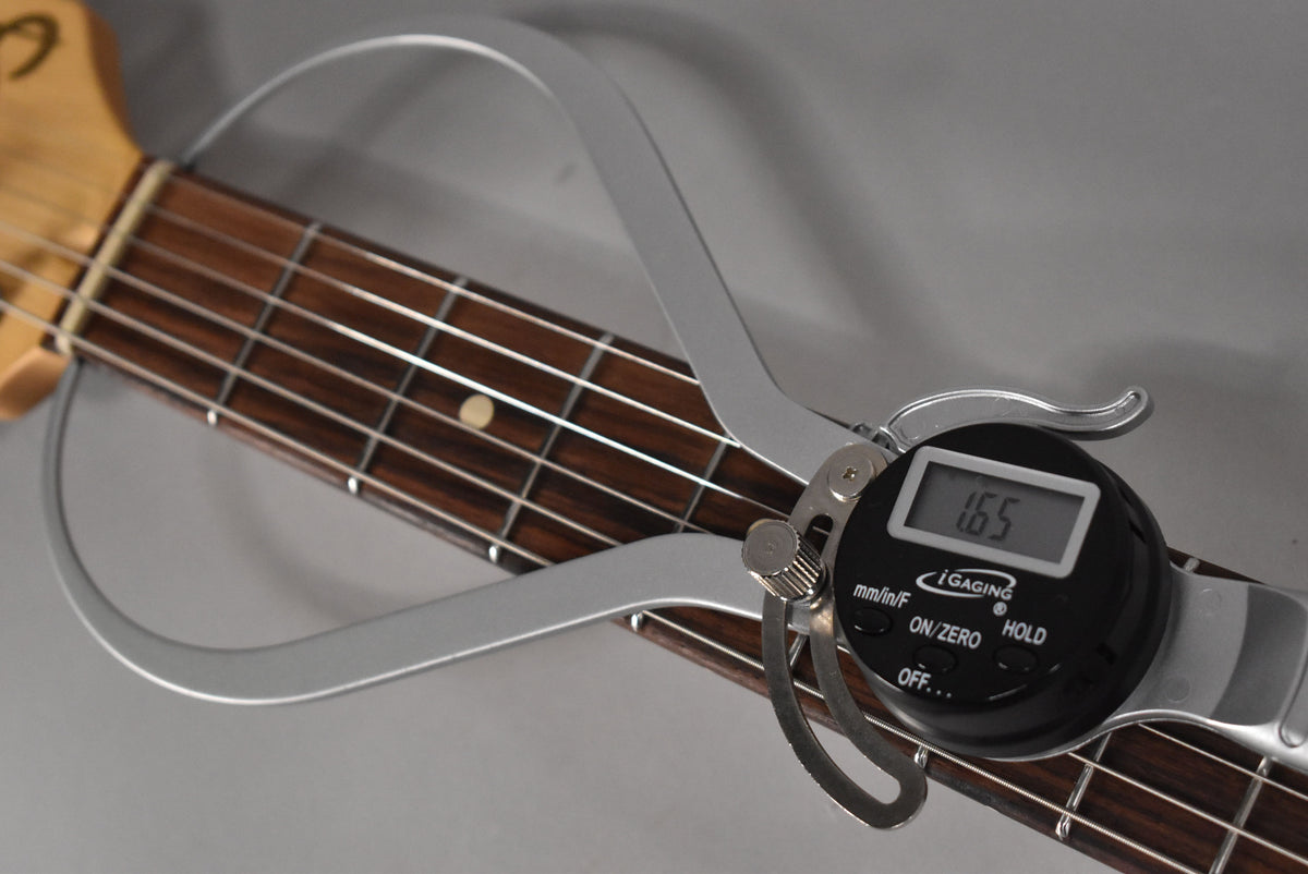 Close-up of the guitar's dark fretboard with frets and a single dot inlay, measured by a digital fret rocker displaying "1.65".