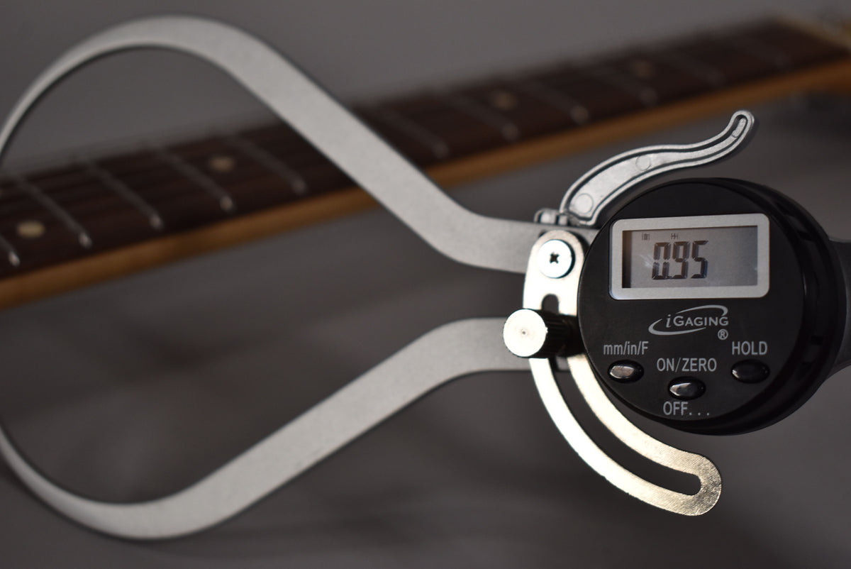 A digital caliper measures the guitar's fret height at 0.95, with the dark rosewood fretboard and frets visible in the background.