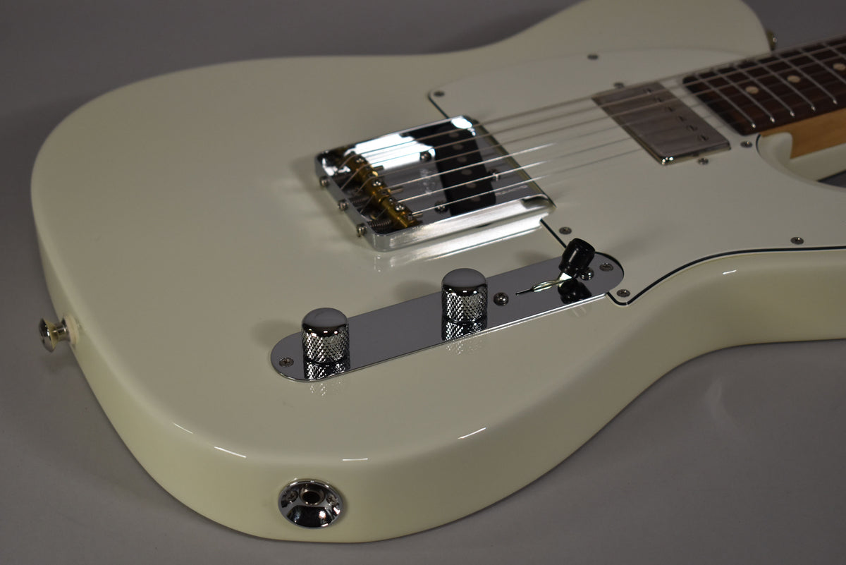 Close-up of the Olympic White guitar body, showing the chrome bridge, control plate with two knurled knobs, and a black switch.