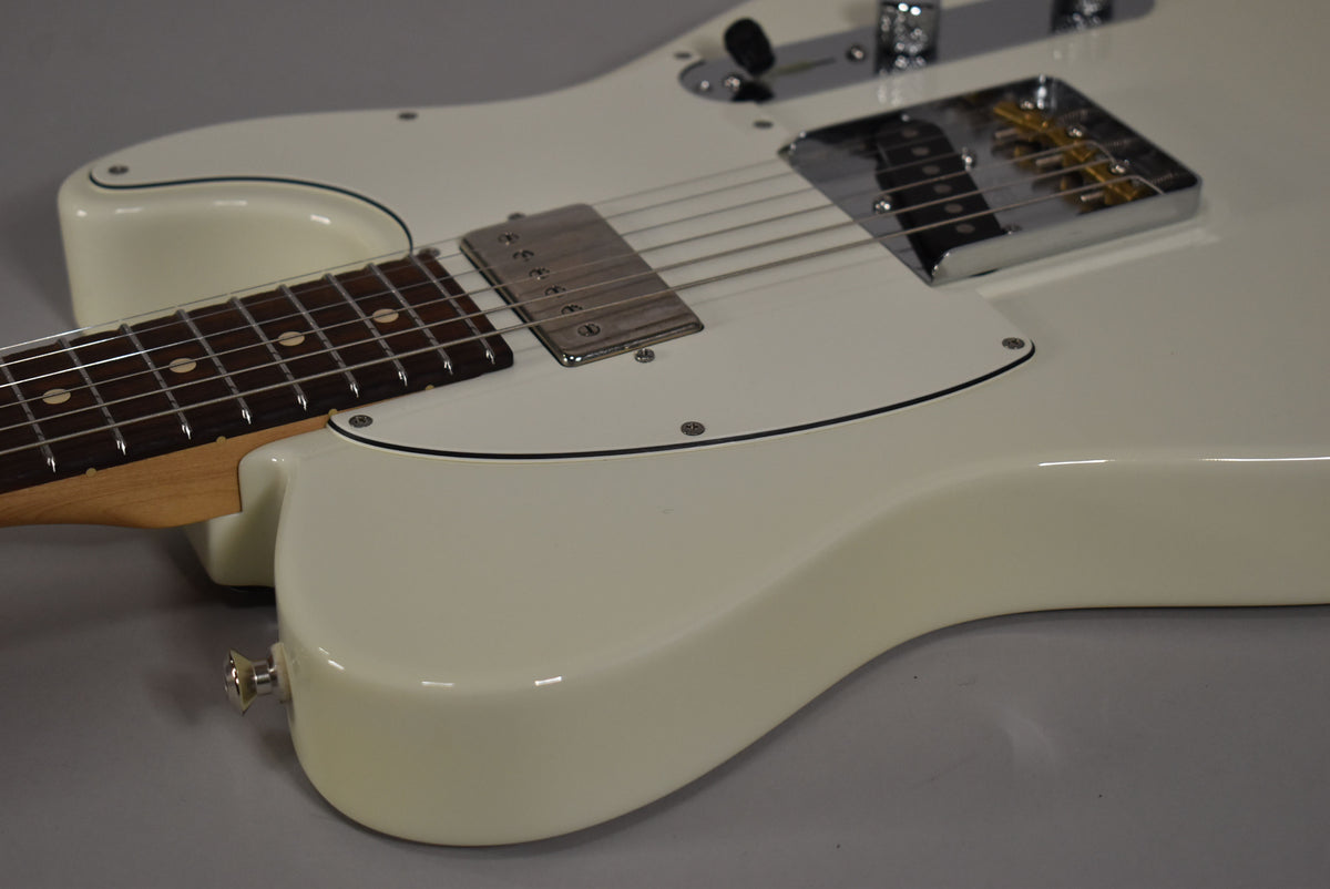 The Olympic White guitar body is angled from the lower left, showing the neck joint, white pickguard, and chrome bridge and humbucker.