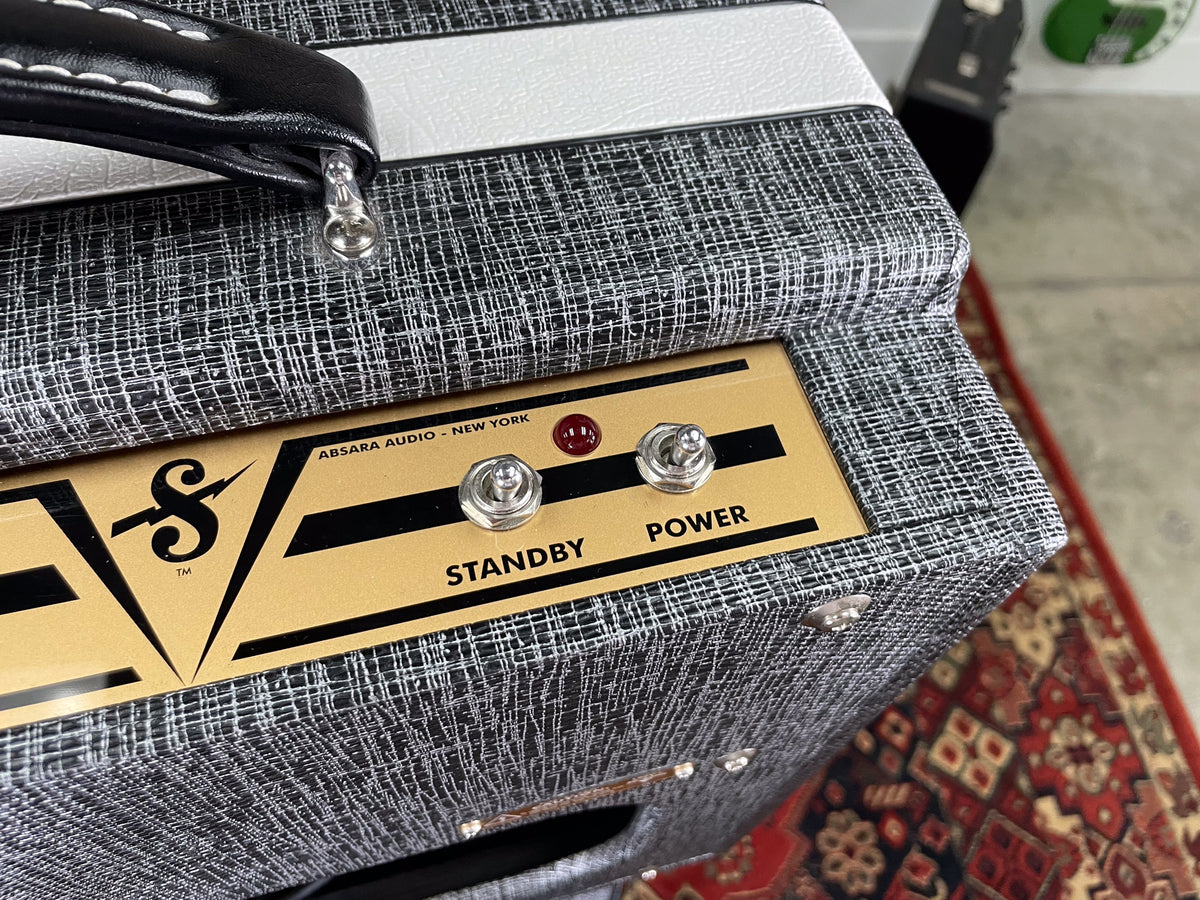 Close-up of the amp's top, showing the black and white textured tolex, gold control panel with two toggle switches, and red jewel light.