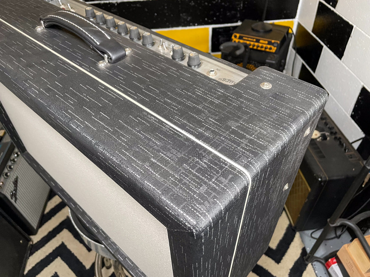 Top-down view of the amp's black textured tolex with white piping, silver control panel, and black leather handle.