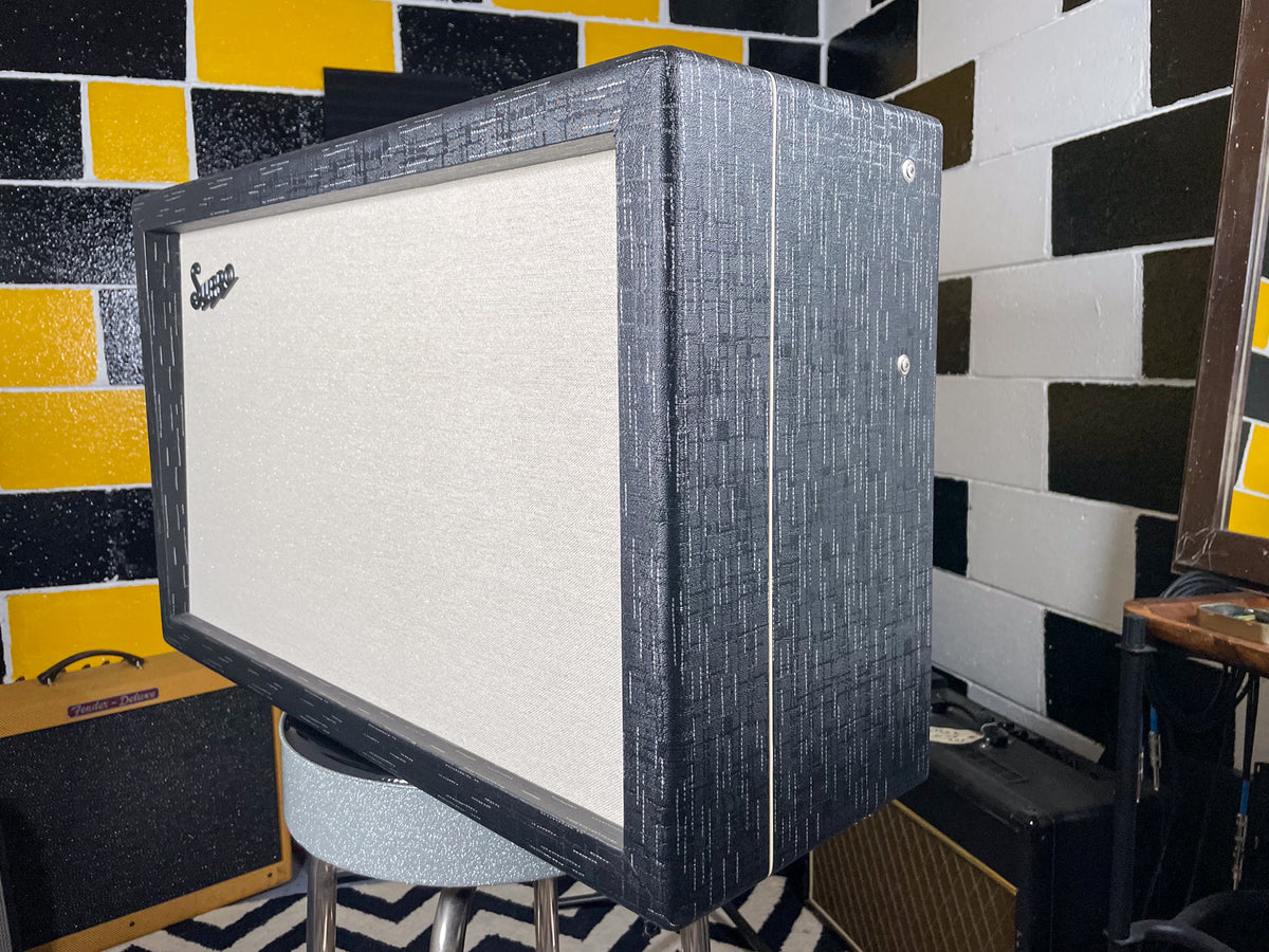 The combo amp is angled, showing its textured dark gray cabinet with white piping and a light gray speaker grille.